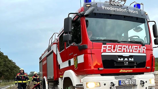 Ein Fahrzeug des Löschzuges Fredersdorf-Nord und daneben zwei Feuerwehrmänner.