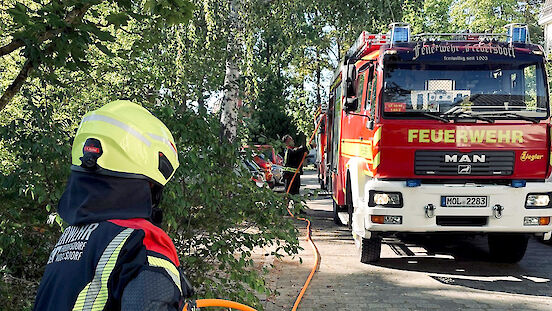 Zwei Feuerwehrmänner rollen einen Schnellangriffsschlauch aus einem Fahrzeug des Löschzuges Fredersdorf-Süd.