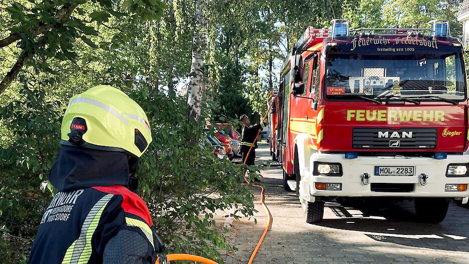 Zwei Feuerwehrmänner rollen einen Schnellangriffsschlauch aus einem Fahrzeug des Löschzuges Fredersdorf-Süd.